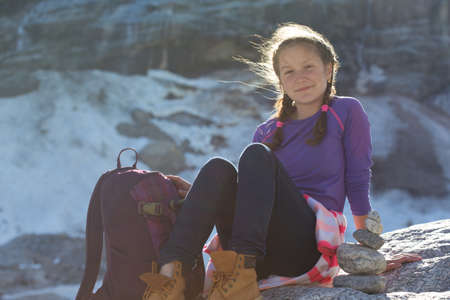 portrait girl  hiker with a backpack sitting on a rock with snow and mountains in the background,  Norwayの写真素材