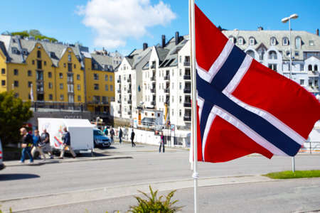 Norwegian flag flying in the background of houses of famous norwegian town Alesundの写真素材