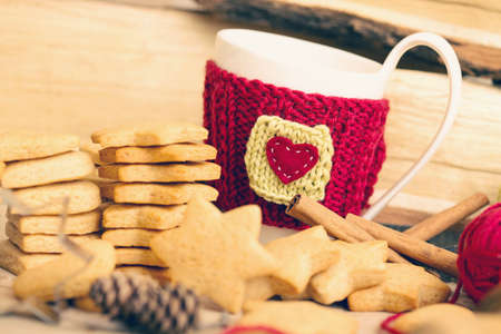 Knitted woolen cups on a wooden table and beautiful delicious christmas gingerbreadの写真素材