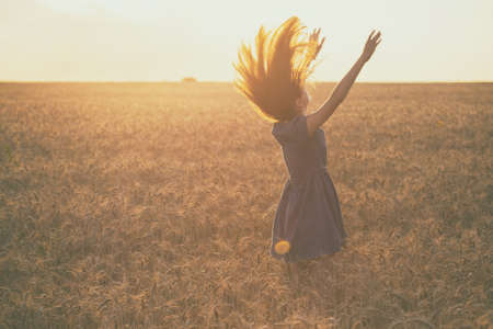 happy young girl joys at the wheat field at the evening timeの写真素材