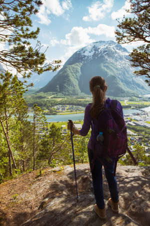 Rampestreken. girl hiker with a backpack and trekking pole standing and looking on Romsdalsfjorden and Andalsnes, Norwayの写真素材