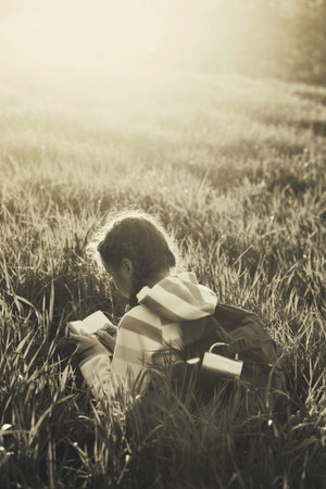 girl hiker sitting on a meadow grass and enjoying a sunset
