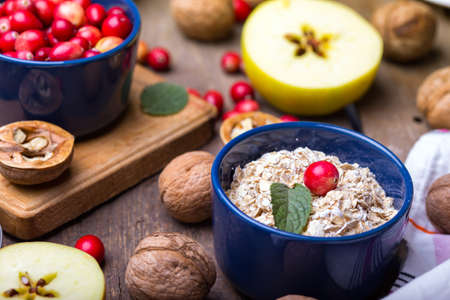 healthy breakfast - oatmeal, cranberries, nuts, apples on a wooden tableの写真素材