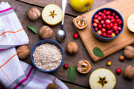 healthy breakfast - oatmeal, cranberries, nuts, apples on a wooden tableの写真素材