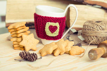 Knitted woolen cups on a wooden table and beautiful delicious christmas gingerbreadの写真素材