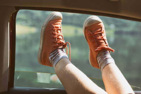 Girl legs in bright sneakers sticking out of the carの写真素材