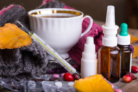 Fall and health care. cup of tea, pills and thermometer on a wooden backgroundの写真素材