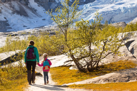 mother and daughter hiking on the lake with  mountains and the glacier Nigardsbreen at the backgroundの写真素材