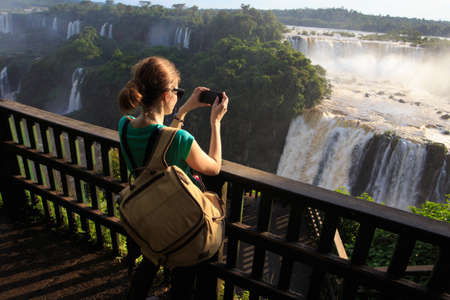 girl taking a photo of Iguassu waterfall with smartphoneの写真素材