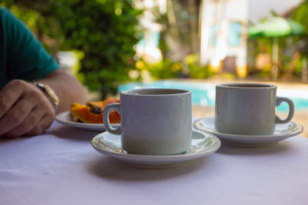 Breakfast - two cups of coffee, rolls and papaya on the pool backgroundの写真素材