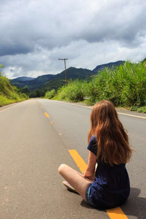 girl at the empty brazilian road at sunny cloudy dayの写真素材