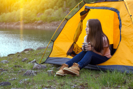 girl hiker in a tent and holding a cup mountains in the background, norwayの写真素材