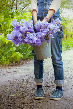 girl holding a bucket in the garden with irisesの写真素材