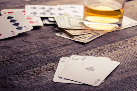 cards, whisky and money lying on a wooden tableの写真素材