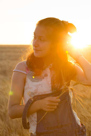 happy young teen girl joys at the wheat field at the evening timeの写真素材