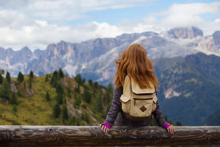 girl hiker sitting  and looking at the snowed mountains. Dolomites, Italy.の写真素材