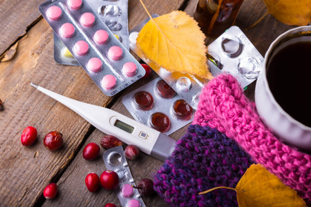 Fall and health care. home pharmacy - cup of tea, pills and thermometer on a wooden background