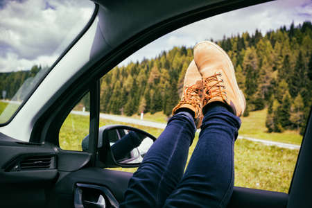 Girl legs in bright boots sticking out of the car. Dolomites, Italy.の写真素材