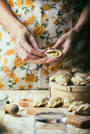Ukrainian traditional bakery products - Making pierogies by female hands. Rustic style. Retro Photoの写真素材