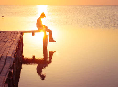 girl sitting on a pier and reading at the sunset time
の写真素材