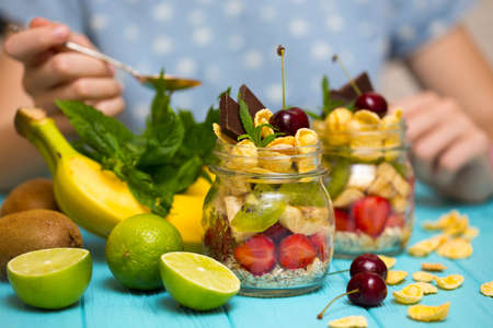 healthy diet. girl hand with a spoon and oatmeal with berries and fruits, measurer. food photographyの写真素材
