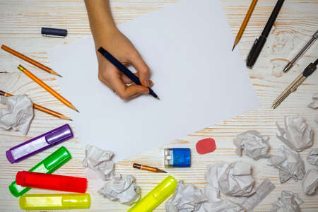 the hand of the girl artist and Album pages, paints, pencils,oil, brush on a wooden backgroundの写真素材