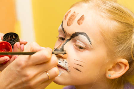 mother painting a face of her daughter like girl cat
の写真素材