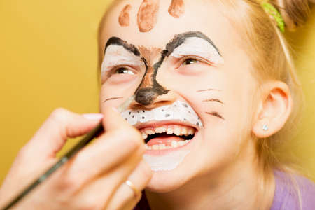 mother painting a face of her daughter like girl cat
の写真素材