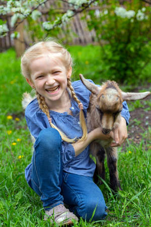 little girl with a goatling in the garden, spring
の写真素材