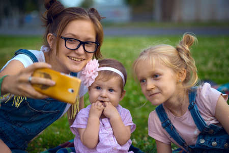 Modern children - girls do selfie sitting on the lawnの写真素材