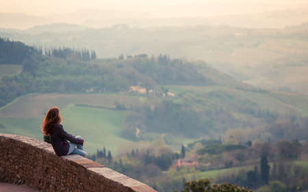 girl looking at the tuscanian landscape with the hills and cypressesの写真素材
