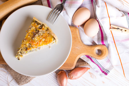 foodphoto - onion pie on a plate, near fork, eggs, onion
