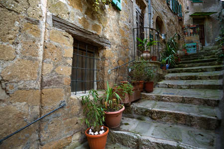 View of the streets in the old  famous tuff city of Sorano. Old staircase with flowers in pots. Tuscany, Italyの写真素材