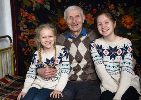 grandfather with granddaughters are sitting in the rural houseの写真素材