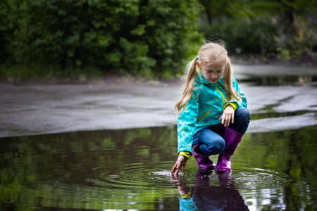 kid girl playing in a puddle on a rainy dayの写真素材