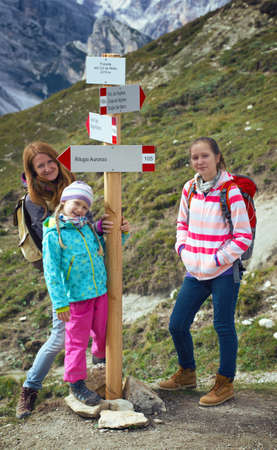 family - mother and two daughters  girls sisters hikers  standing near sign for direction at the mountains Dolomites, Italy. Tre Cime di Lavaredoの写真素材
