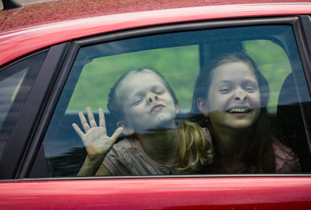 children making funny faces sitting at the car