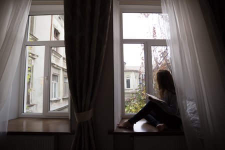 teen girl sitting on a windowsill with a book  in the children's room