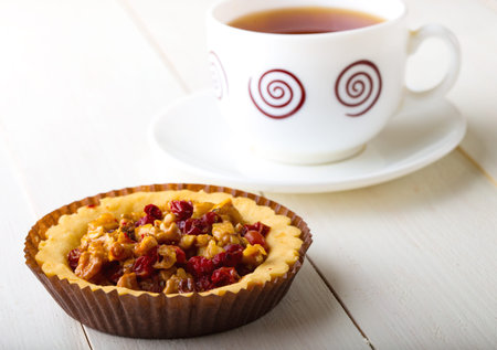 berry tartlets and cup of tea on a white wooden backgroundの写真素材