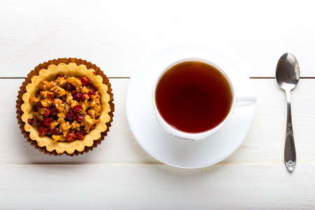 berry tartlets and cup of tea on a white wooden backgroundの写真素材