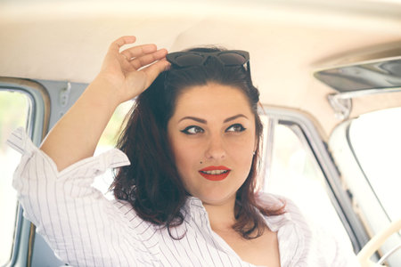 portrait of beautiful girl in a retro car in style pin up