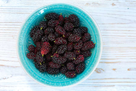 ripe mulberry in bowl on a wooden tableの写真素材