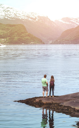 tourist man and girl with a backpack standing on the shore Hardangerfjorden, Norway