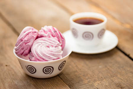 fruit marshmallows and the cup of tea on a wooden backgroundの写真素材