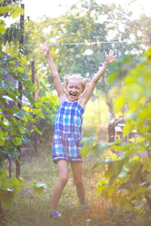summer - Little girl having fun in the garden under rainの写真素材