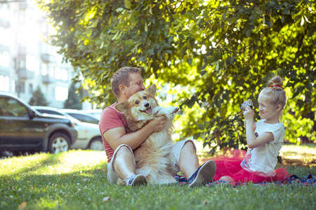 Happy family - little pretty girl with retro camera  taking a picture of father and dogの写真素材