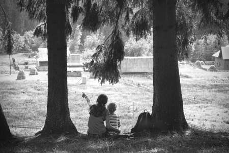 happy family - girls hiker with a backpack sitting on the background of mountains and the village. Vorokhta - Ukrainian landscape.の写真素材