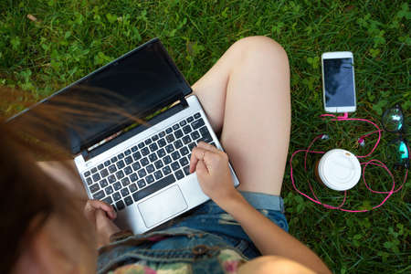 Teen girl sitting with a laptop at the  green lawnの写真素材