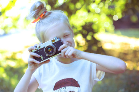 little pretty girl with retro camera outdoor