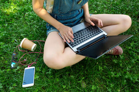 Teen girl sitting with a laptop at the  green lawnの写真素材